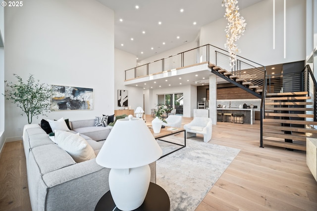 living area featuring a high ceiling, stairway, wood finished floors, and recessed lighting