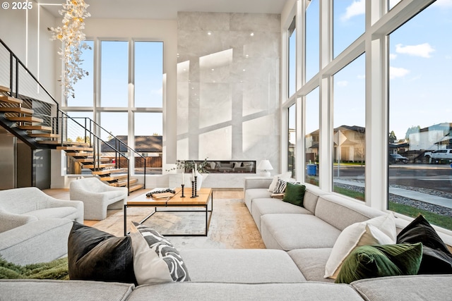 living area featuring a healthy amount of sunlight, stairs, a high ceiling, and wood finished floors