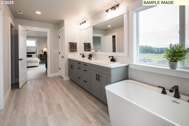 8002 N Haregrave St, Camas, WA 98607 - full bathroom featuring connected bathroom, wood finished floors, a sink, a soaking tub, and double vanity
