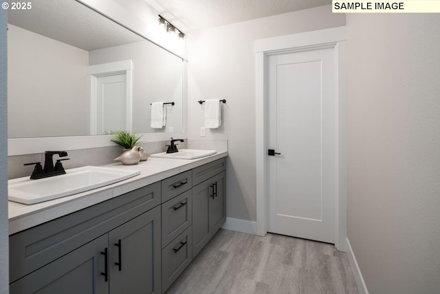 8002 N Haregrave St, Camas, WA 98607 - bathroom featuring double vanity, a sink, baseboards, and wood finished floors