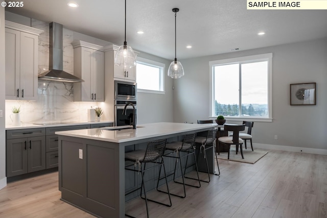 8002 N Haregrave St, Camas, WA 98607 - kitchen featuring a kitchen island with sink, stainless steel appliances, a sink, backsplash, and wall chimney exhaust hood