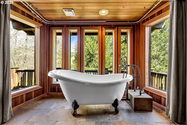 sunroom with wooden ceiling, baseboards, stone tile floors, and wooden walls