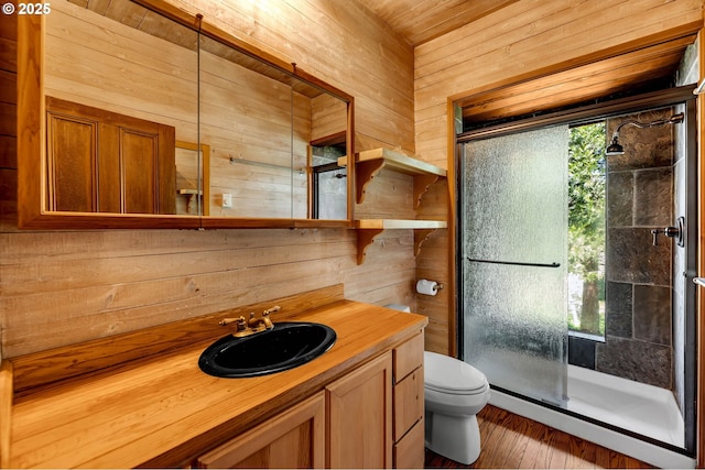 bathroom featuring wood walls, toilet, vanity, and a shower