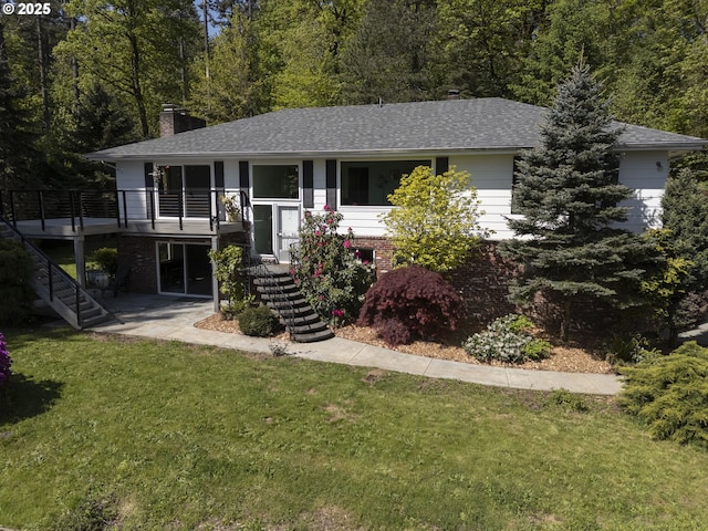 view of front facade featuring stairway, a shingled roof, a chimney, and a front yard
