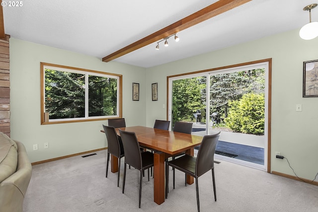 dining space featuring light colored carpet, beamed ceiling, baseboards, and visible vents