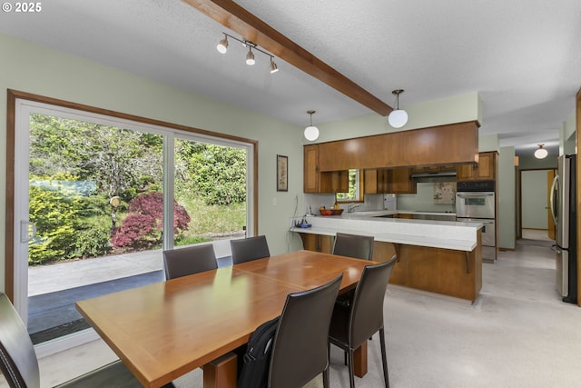 dining area featuring a textured ceiling and beamed ceiling