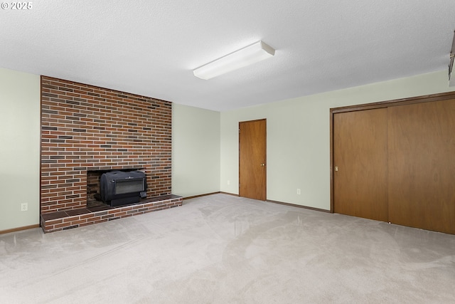 unfurnished living room with baseboards, a textured ceiling, a wood stove, and carpet