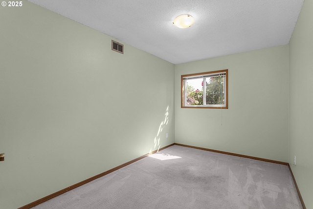 spare room featuring a textured ceiling, carpet floors, baseboards, and visible vents