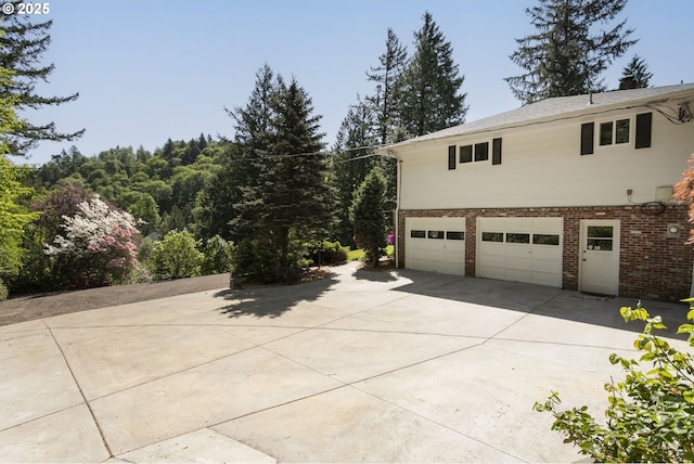 view of home's exterior featuring a garage, brick siding, and driveway
