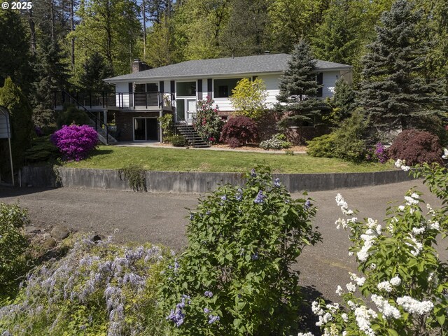 view of front of property featuring a chimney, stairs, a wooden deck, and a front lawn