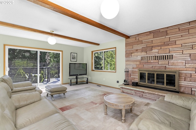living area featuring a wealth of natural light, baseboards, beam ceiling, and a stone fireplace