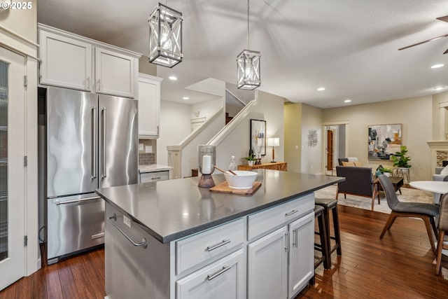 kitchen with dark countertops, open floor plan, white cabinetry, and high quality fridge