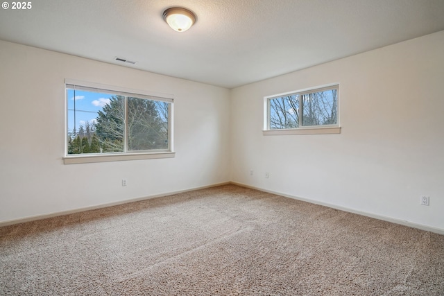 carpeted spare room featuring a textured ceiling, visible vents, and baseboards