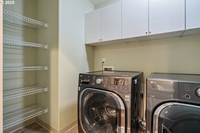 washroom with cabinet space, baseboards, and separate washer and dryer