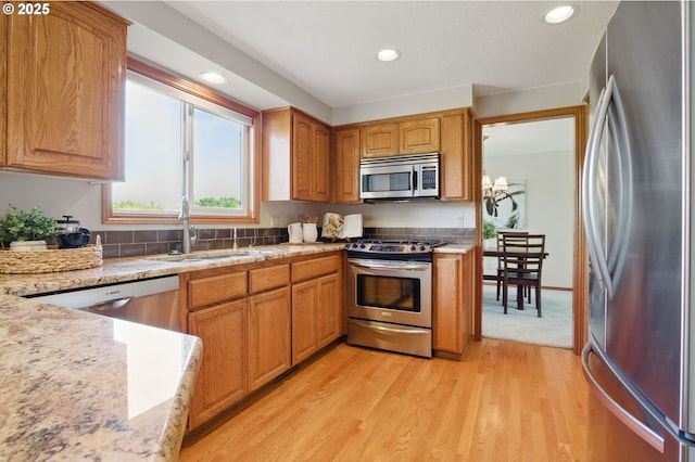 8355 SW 159th Pl, Beaverton, OR 97007 - kitchen with appliances with stainless steel finishes, a sink, light wood-style floors, recessed lighting, and light stone countertops