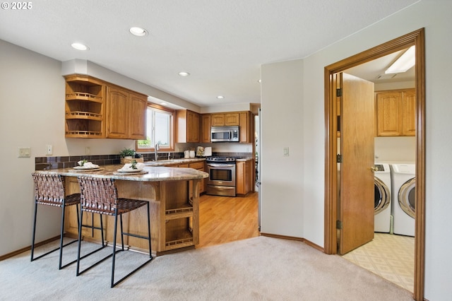8355 SW 159th Pl, Beaverton, OR 97007 - kitchen with appliances with stainless steel finishes, separate washer and dryer, open shelves, a peninsula, and a sink
