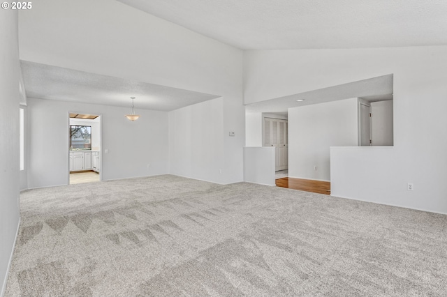 empty room featuring carpet floors, vaulted ceiling, and a textured ceiling