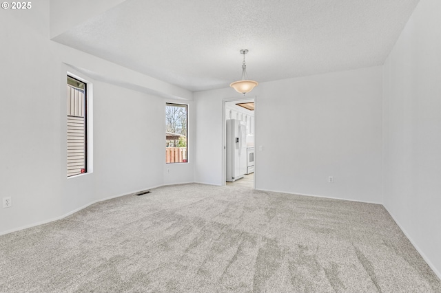 unfurnished room featuring carpet floors, visible vents, and a textured ceiling