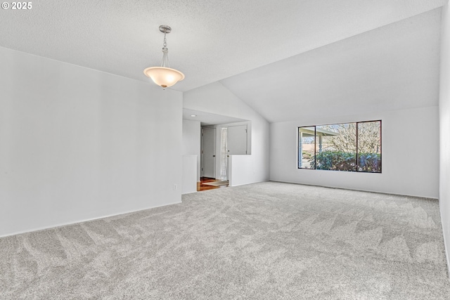 unfurnished living room featuring vaulted ceiling, a textured ceiling, and carpet