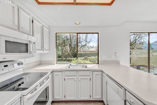 kitchen with white appliances, white cabinetry, light countertops, and a sink