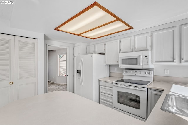 kitchen featuring light countertops, white appliances, a sink, and white cabinetry