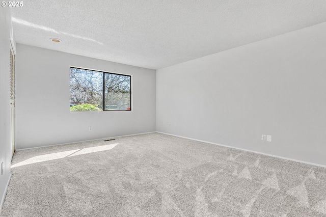 carpeted empty room featuring a textured ceiling, visible vents, and baseboards