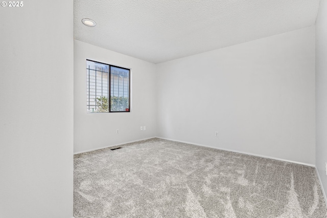 unfurnished room featuring carpet floors, baseboards, visible vents, and a textured ceiling