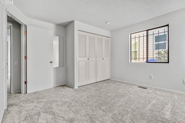 unfurnished bedroom featuring a textured ceiling, a closet, carpet flooring, and visible vents