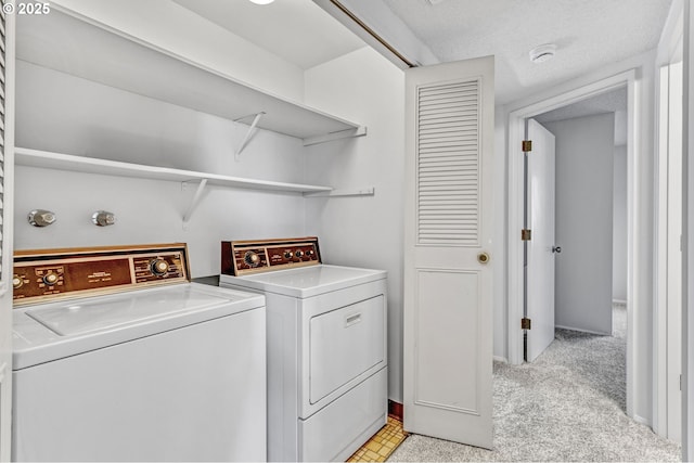 washroom with light carpet, laundry area, washer and clothes dryer, and a textured ceiling