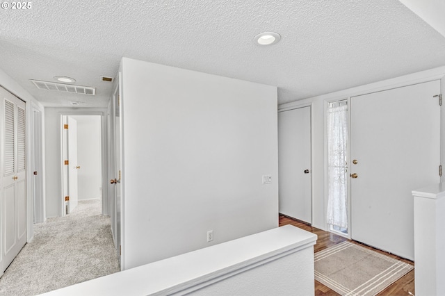 interior space with visible vents, a textured ceiling, and carpet flooring