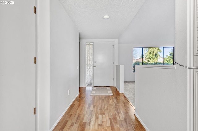 foyer entrance featuring light wood-style floors, a textured ceiling, and baseboards