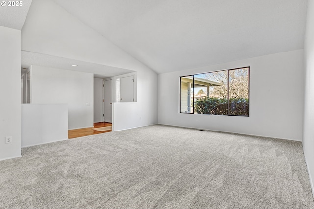 carpeted empty room with high vaulted ceiling and visible vents