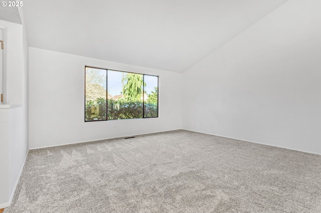 carpeted spare room with visible vents and vaulted ceiling