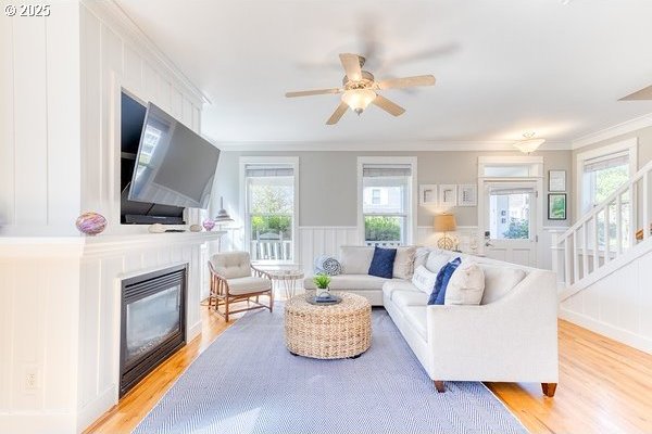 2752 SW Beach Ave, Lincoln City, OR 97367 - living area with a ceiling fan, light wood-style flooring, a glass covered fireplace, a decorative wall, and crown molding