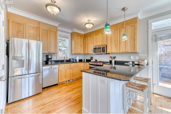 2752 SW Beach Ave, Lincoln City, OR 97367 - kitchen featuring a sink, a peninsula, light wood-style flooring, light brown cabinets, and appliances with stainless steel finishes