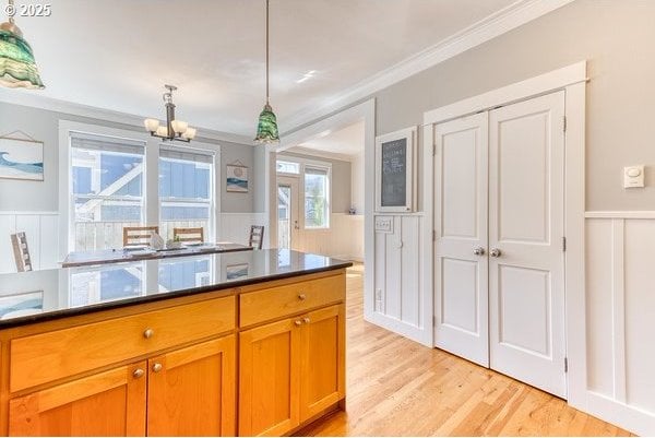 2752 SW Beach Ave, Lincoln City, OR 97367 - kitchen featuring hanging light fixtures, a notable chandelier, wainscoting, light wood-style floors, and ornamental molding