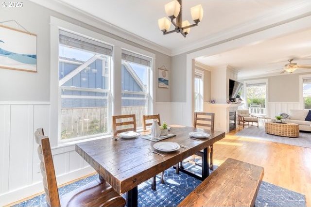 2752 SW Beach Ave, Lincoln City, OR 97367 - dining area with ceiling fan with notable chandelier, a decorative wall, a wainscoted wall, wood finished floors, and crown molding