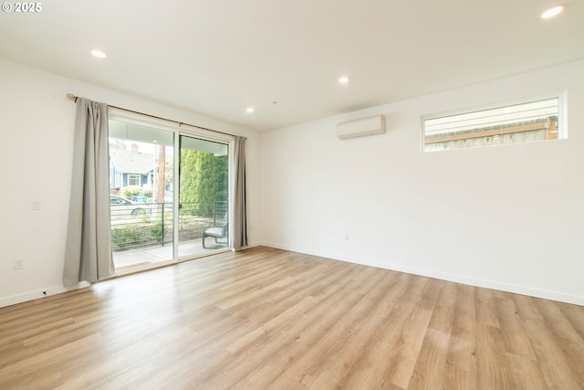 empty room featuring baseboards, recessed lighting, a wall mounted AC, and light wood-style flooring