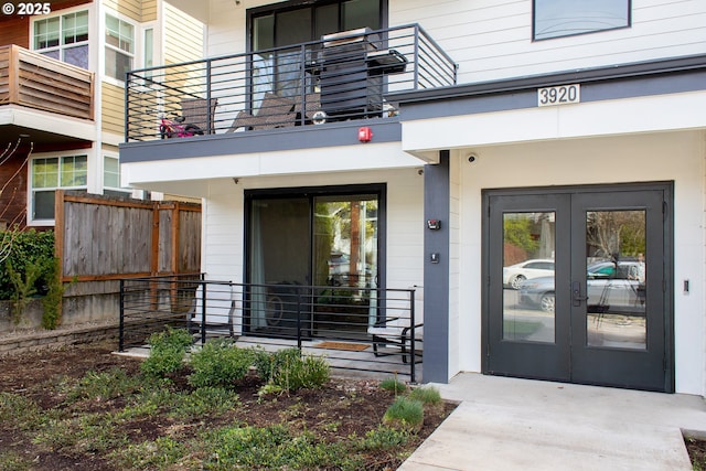 view of exterior entry featuring fence and french doors