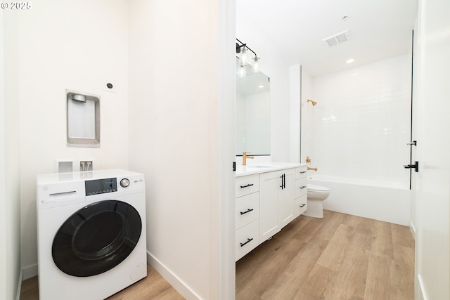laundry area with a sink, light wood-type flooring, laundry area, washer / clothes dryer, and visible vents