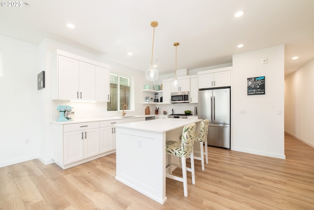 kitchen featuring a center island, open shelves, light wood-style floors, stainless steel appliances, and light countertops
