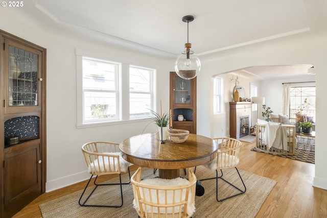 5835 NE 23rd Ave, Portland, OR 97211 - dining space featuring arched walkways, light wood-style floors, and a fireplace with flush hearth