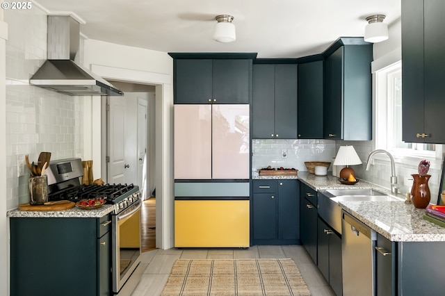 5835 NE 23rd Ave, Portland, OR 97211 - kitchen with stainless steel appliances, wall chimney exhaust hood, tasteful backsplash, light stone countertops, and light tile patterned floors