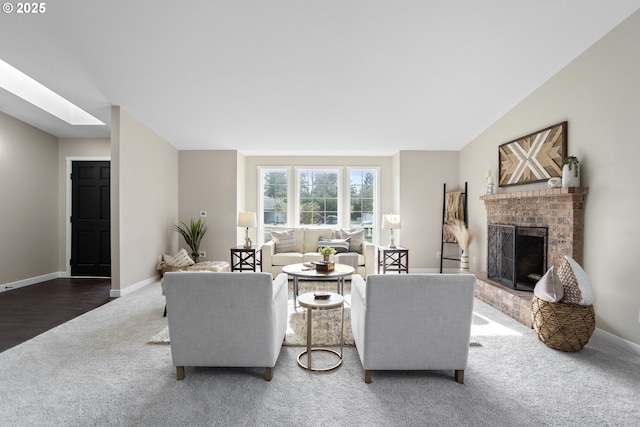 living room with lofted ceiling with skylight, a brick fireplace, baseboards, and carpet floors