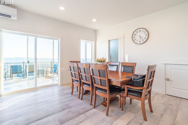 dining room featuring an AC wall unit and light hardwood / wood-style floors