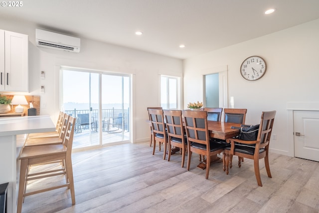 dining area featuring a wall unit AC and light hardwood / wood-style flooring