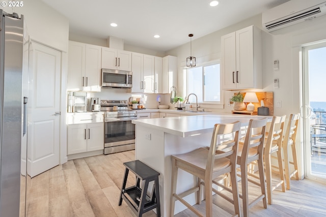 kitchen with white cabinetry, stainless steel appliances, decorative light fixtures, and a breakfast bar area