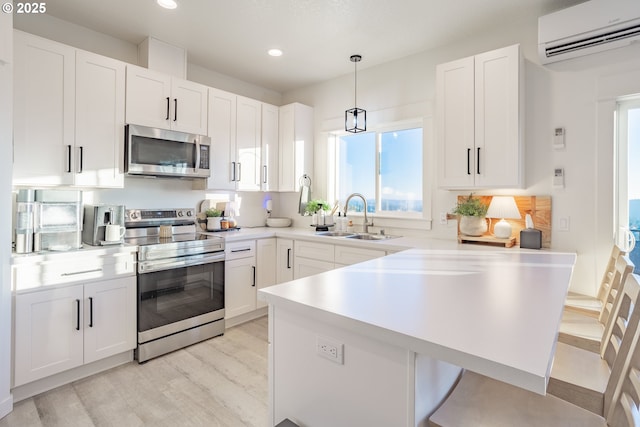 kitchen featuring sink, white cabinetry, hanging light fixtures, stainless steel appliances, and an AC wall unit