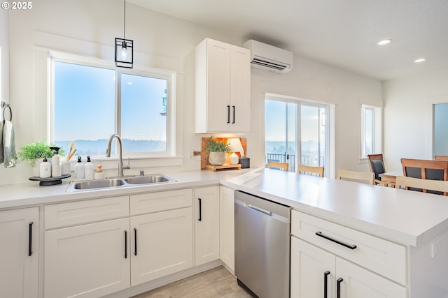 kitchen with an AC wall unit, white cabinetry, dishwasher, sink, and hanging light fixtures