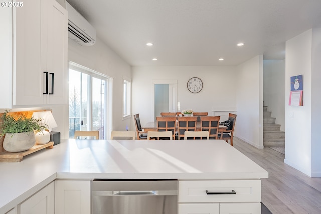 kitchen featuring an AC wall unit, white cabinets, and light hardwood / wood-style floors